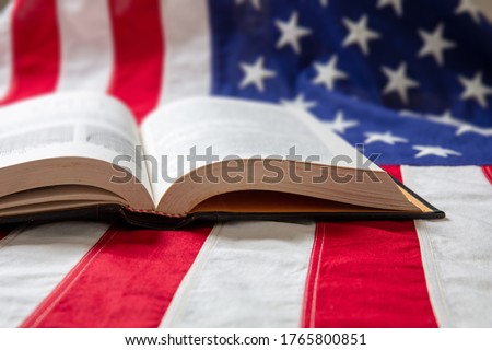 Book open on USA flag background, closeup view. United States of America education, culture, religion concept