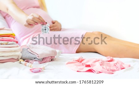Pregnant woman with an alarm clock. Selective focus. people.