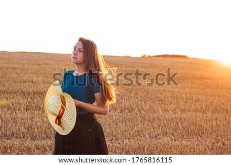 Adorable young girl in summer wheat field with straw hat in hands. Woman with long blonde hair on countryside sunset landscape.Family farming agriculture concept.Local travel tourist,holiday traveling