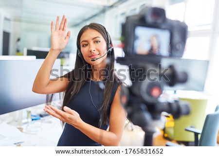 Young businesswoman with headset produces an instructional video or makes an online reportage live Royalty-Free Stock Photo #1765831652