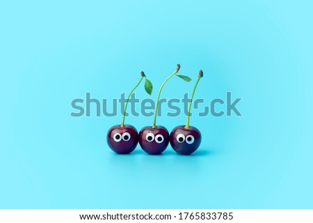 Cherry with eyes on a blue background. Funny vegetables and fruits for children. Baby food concept,  food face.
