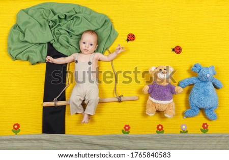 Happy laughing child boy on swing. Funny active child having fun on. Beautiful smiling boy playing on playground on a summer day outdoors. Happiness, active leisure, childhood lifestyle concept