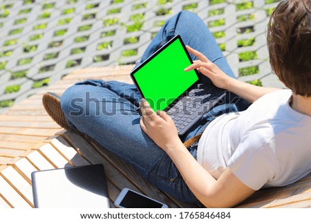 Woman using a tablet with empty green screen, mockup for your app design.