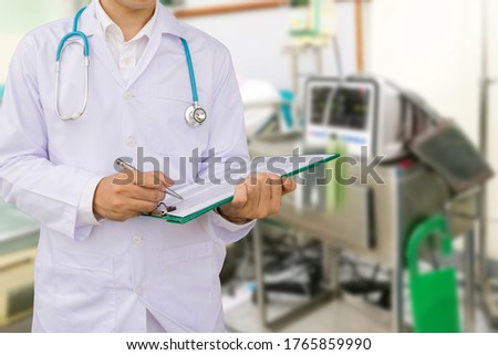 Closeup portrait of a doctor with stethoscope holding folder with hospital background.