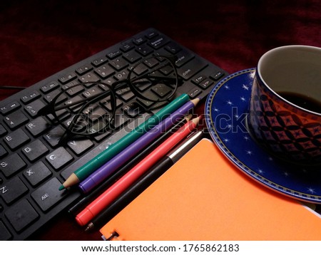 keyboards, reading glasses, light green purple pens, notebooks and accompanied by a cup of black coffee. food for web site advertisement background