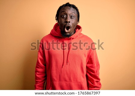 Young african american sporty man wearing sweatshirt with hoodie over yellow background afraid and shocked with surprise expression, fear and excited face.