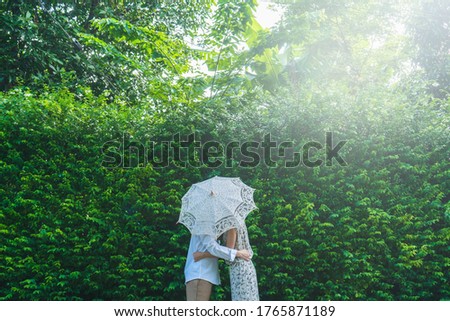 Asian couple kissing behind umbrella