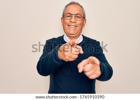 Senior handsome grey-haired man wearing sweater and glasses over isolated white background pointing fingers to camera with happy and funny face. Good energy and vibes.