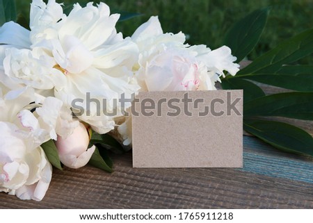 Mock up, greeting card. white flowers of peonies and a card card on a wooden background. postcard