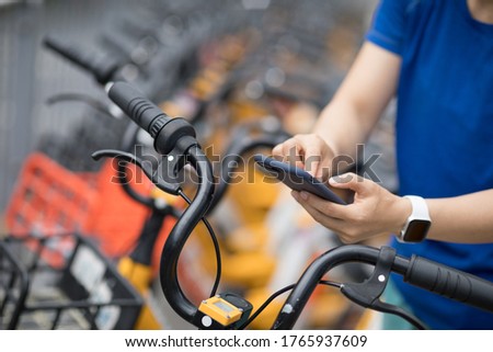 People using smartphone scanning the QR code of shared bike in city