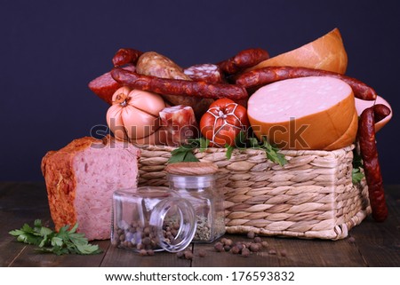 Lot of different sausages in basket on wooden table on black background
