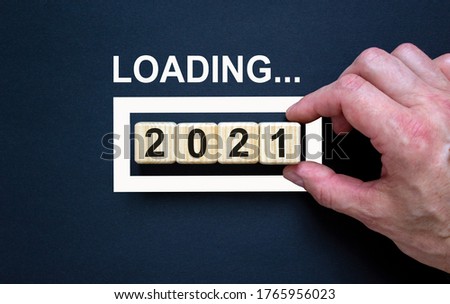Loading new year 2021 with hand putting wood cube in progress bar. Business concept.