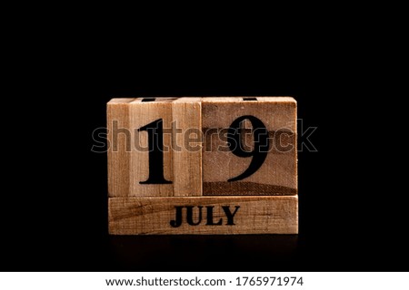 wooden calendar 19 July word on black background with copy space , selective focus at the calendar