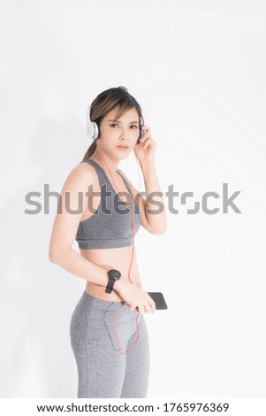 Fitness woman listening to music wearing white music headphones, enjoys sports and healthy lifestyle isolated on a white background. She is relaxing and happiness.