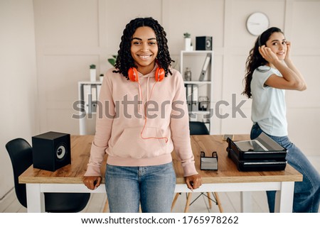 Two women in headphones listening to music indoors
