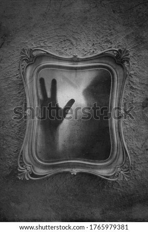 Horror concept of a ghostly figure trapped in a mirror. With a grunge, blurred, textured, black and white edit. Royalty-Free Stock Photo #1765979381