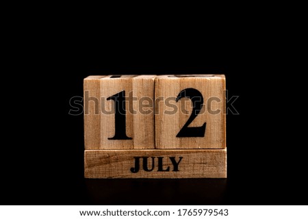 wooden calendar 12 July word on black background with copy space , selective focus at the calendar