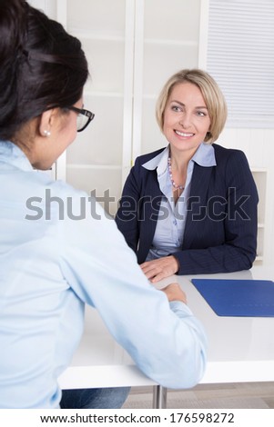 Interview with two businesswomen at desk at office.