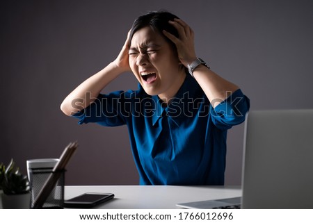 Asian woman in blue shirt angry and shouting, at office. isolated on background. Low key.