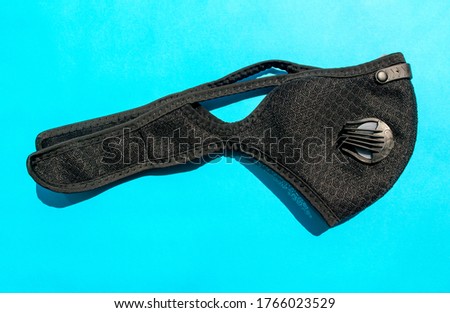 Black dust mask with filters on blue background. Top view. Safety breathing mask. PPE