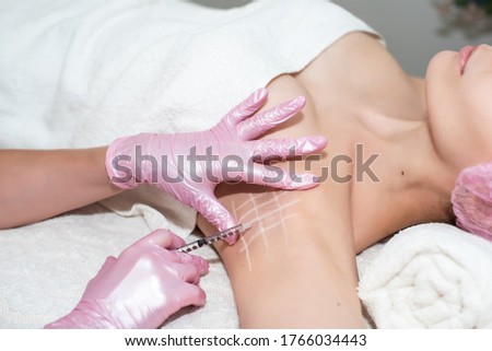 Treatment of hyperhidrosis. in the cosmetologist's office, female hands in pink gloves inject a young woman in the armpit. healthy body concept, self-care. stop sweating and bad smell Royalty-Free Stock Photo #1766034443