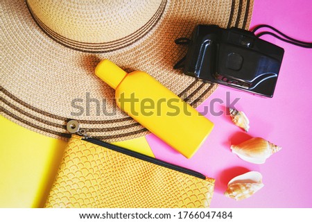 Sun hat, sunscreen cream, camera, cosmetic bag and seashells. Summer travel photography, beach essentials. Flat lay beauty photo