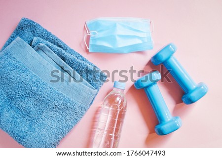 Opening of fitness centers after removal of coronavirus restrictions. Flat lay composition stock photography. Towel, disposable mask, bottle with clear water, dumbbells