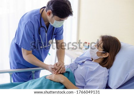 Asian male doctors wear uniforms and medical masks, holding hands with middle-aged female patients to encourage patients. encourage and empathy at nursing hospital ward. Royalty-Free Stock Photo #1766049131