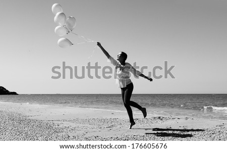 Young woman  walking on the beach with pink balloons. Photo in old style colors.