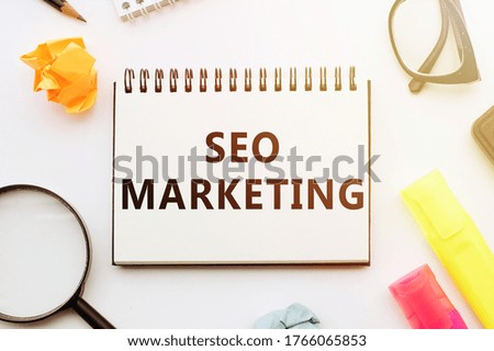 Writing SEO and MARKETING Concepts in Notebook on office table