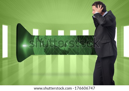 Stressed businessman with hands on head against bright green room with windows