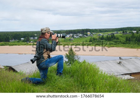 A photographer with a camera takes a landscape on the street.