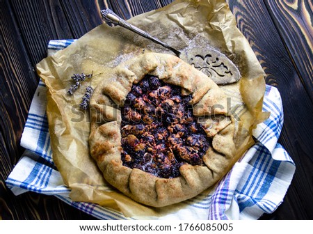 Homemade french plum fruit galette pie on the black wooden desk with linen fabric and antique silver cutlery