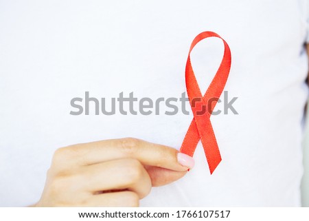 A woman holding a red ribbon emerges from a critical situation after overcoming AIDS