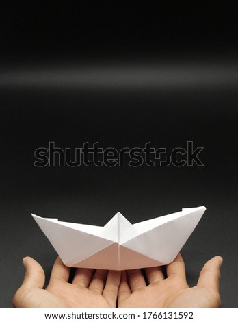 Hands holding paper boat, origami concept