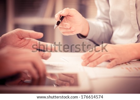 Cropped image of a businesswoman holding a pen and pointing at something while dealing with her colleague on the foreground  Royalty-Free Stock Photo #176614574