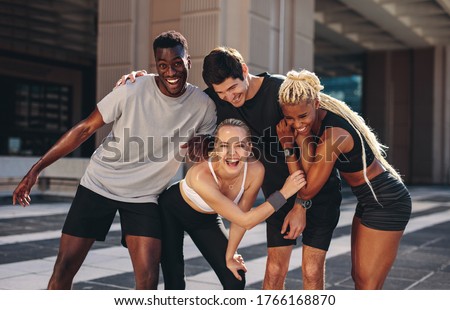 Multi-ethnic group of runners standing together after exercising session outdoors and smiling. Group of men and women in sportswear standing together and laughing after workout training. Royalty-Free Stock Photo #1766168870