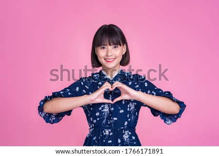 Asian attractive cute short hair woman happy smiling making love care affection heart hand sign presenting confident independent mother businesswoman wearing dress pink isolated background portrait 