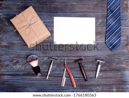 Razors, brush, gift, and empty card on a wooden background. View from the top.
