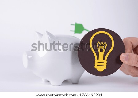 A light bulb sign near a piggy bank- a concept of electricity price