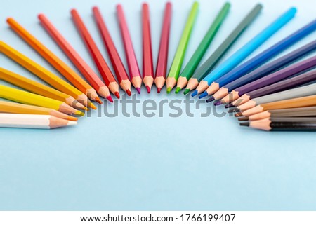 colourful pencils laid out in a fan shape like a rainbow on a table 