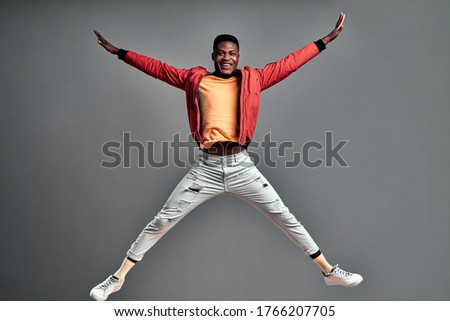 Young happy afro american man jumps in joy over grey background. Copy space