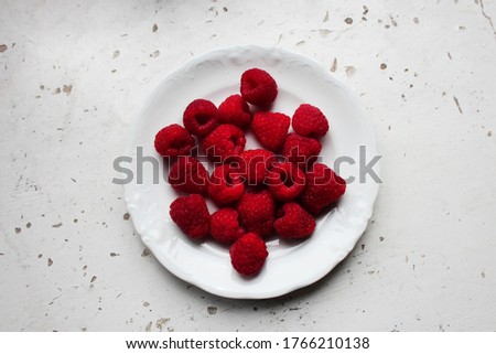Pink raspberries on a white plate on the rustic old table. 