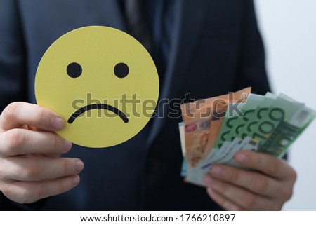 A man holding money and a sad smiley face