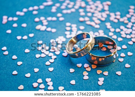 Heart shaped im confetti on a blue background. Sequins and silver wedding rings. Top view. Wedding concept, Valentine's day. Love and romance. Romantic date.Valentine's day.