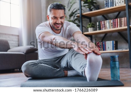 Handsome man doing hamstring stretch exercise at home. Royalty-Free Stock Photo #1766226089