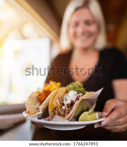 Smiling women with taco food plate in her hand