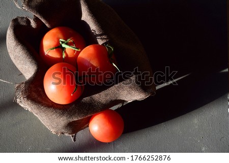 Fresh natural tomatoes, on a cloth inside a box, entrance light through the window