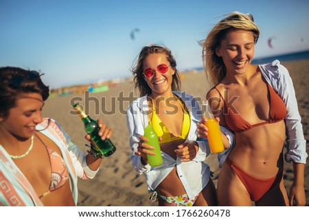 Three friends walking on the beach and laughing on a summer day, enjoying vacation.