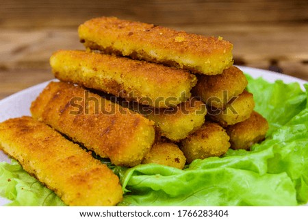 Baked fish sticks and lettuce leaves in plate